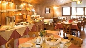 A dining area with multiple tables set for breakfast, featuring bread, pastries, and coffee. - Tautermann Garni (Innsbruck)