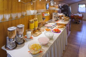 A buffet setup with various food items and beverages, including bowls of cereal, fruits, and pastries. - Tautermann Garni (Innsbruck)