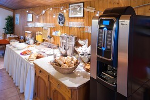 Un bufé de desayuno con diferentes opciones de comida, una máquina de café y un reloj en la pared.