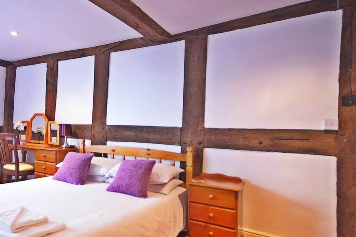 A bedroom with a wooden bed frame, a nightstand, and a dresser.