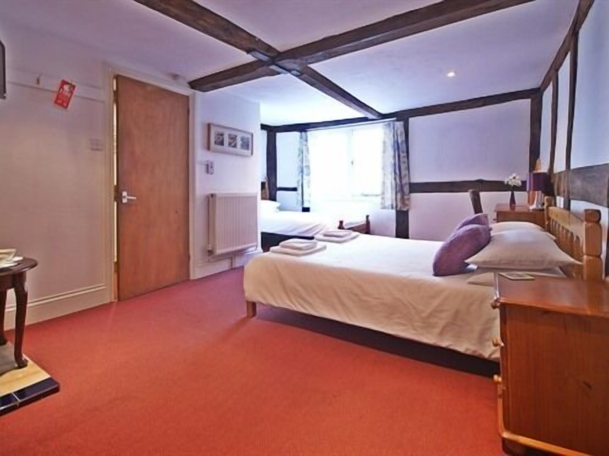 A hotel room with a large bed, a wooden dresser, a radiator, and a door.