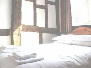 A room with a wooden headboard, a neatly made bed with white linens, and a window with curtains. - The Inn at Bromyard (Bromyard)