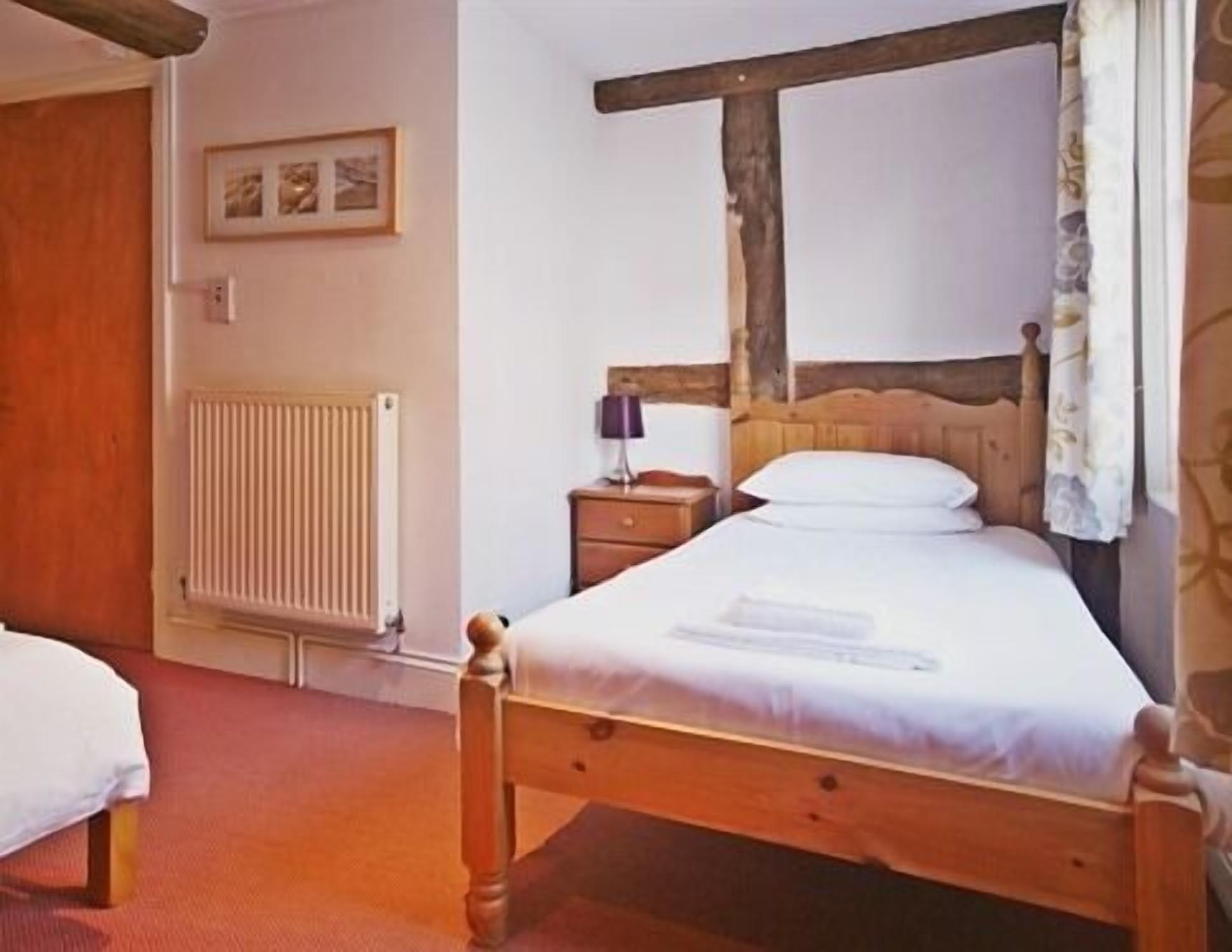 A wooden bed with a headboard, a bedside table, and a lamp.