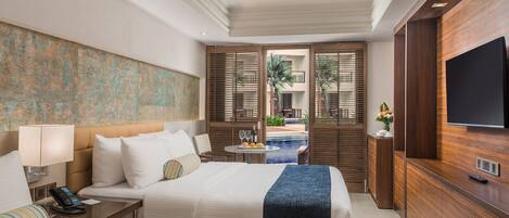A hotel room with two beds, a TV, a phone, and a view of an outdoor pool area.