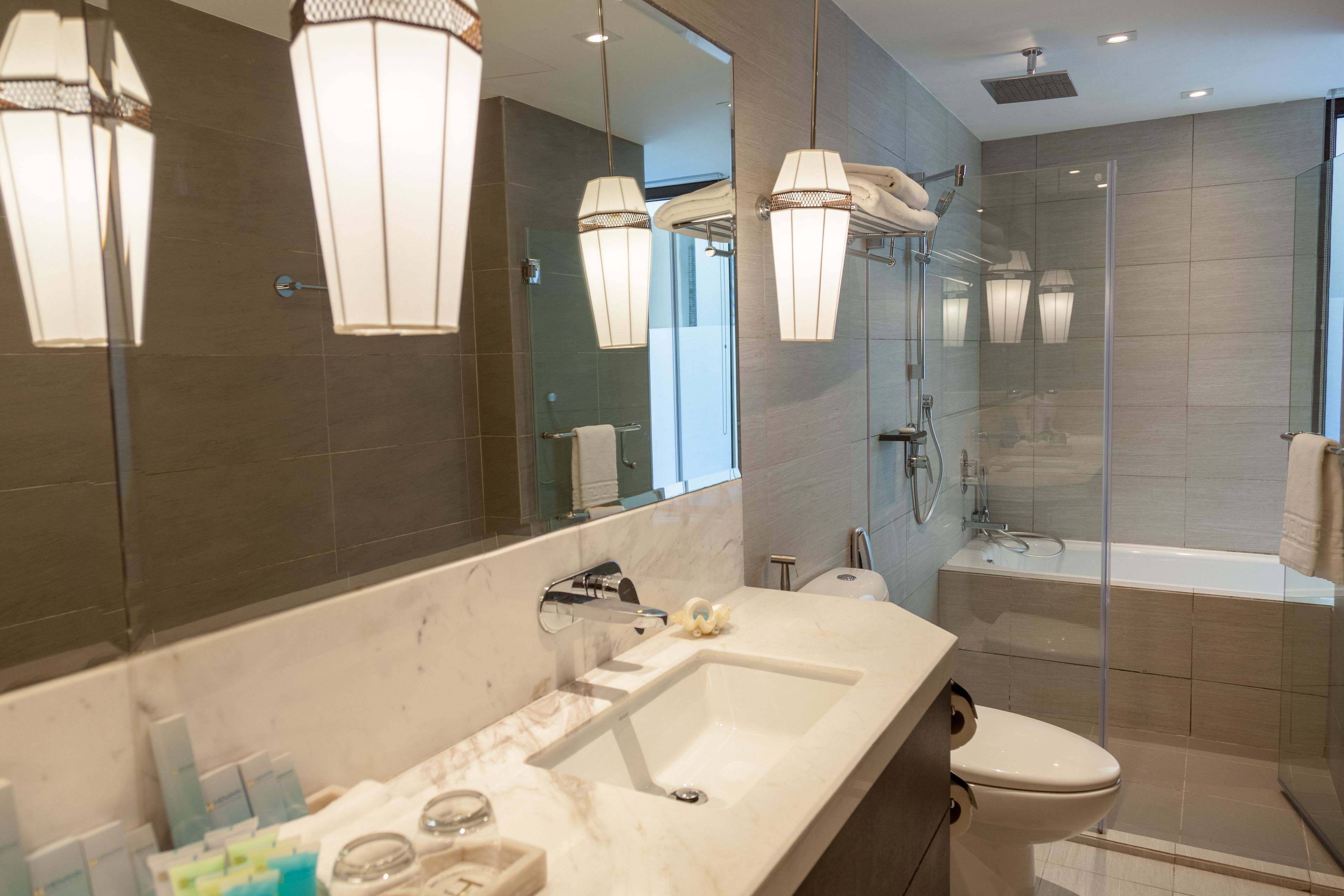Un baño moderno con un espejo grande, un lavabo, un inodoro y una zona de ducha.