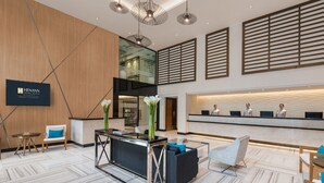A modern hotel lobby with a reception desk, seating area, and a large mirror reflecting the interior. - Henann Prime Beach Resort (Boracay Island)