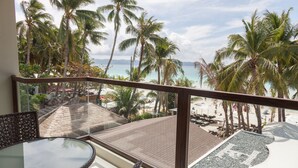 A balcony with a glass table and chairs, overlooking a beach with palm trees and a clear sky. - Henann Prime Beach Resort (Boracay Island)