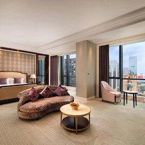 Ein modernes Hotelzimmer mit Bett, Sofa, rundem Tisch und Blick auf die Stadt.