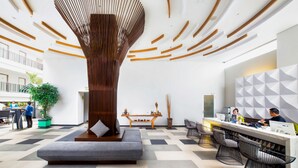 Un vestíbul modern amb una escultura de fusta al centre, una taquilla d'eixida i zones d'estar.