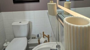 Une salle de bain équipée de toilettes, d’un lavabo, d’un miroir et de tableaux représentant un taureau lisant un journal.