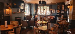 L’intérieur de ce restaurant est chaleureux, avec ses tables et ses chaises en bois, des tableaux encadrés qui ornent les murs et une fenêtre laissant entrer la lumière naturelle.