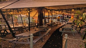 An outdoor seating area with picnic tables and a covered section. - The Crafty Cow (Bristol)