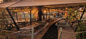 Un espace extérieur aménagé avec des tables de pique-nique et une partie abritée.