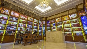 A bookstore with multiple shelves of books and magazines, a central counter, and a chandelier. - Vienna International Hotel (Changsha)