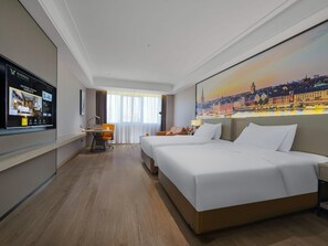 A hotel room with a large bed, a desk with a chair, a television, and a cityscape painting on the wall. - Vienna International Hotel (Changsha)
