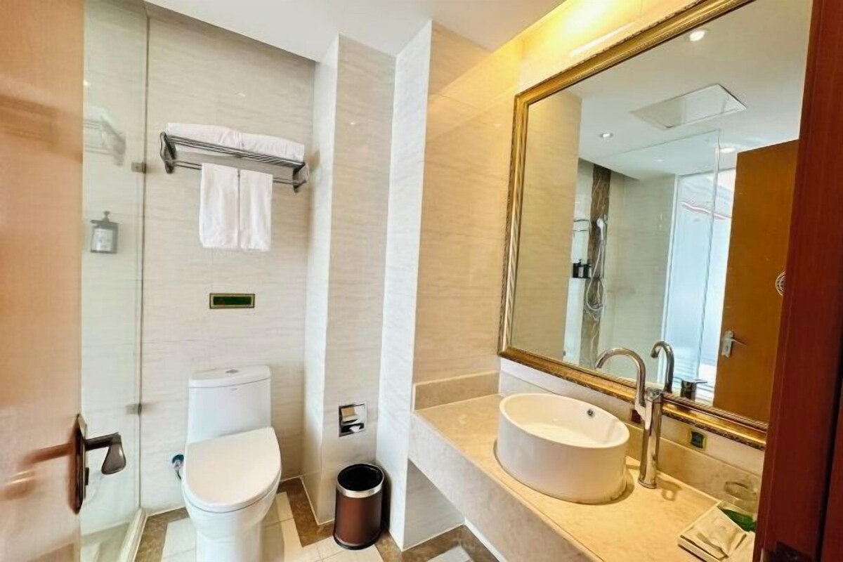 A modern bathroom with a toilet, sink, and large mirror.