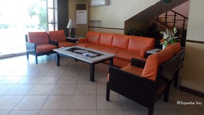 A lobby with orange sofas, a coffee table, and a staircase. - Mo2 Days Inn (Bacolod)