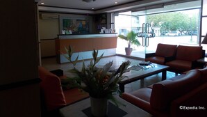 A reception area with a counter, seating, and a large window with a view of the street. - Mo2 Days Inn (Bacolod)