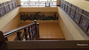 A staircase with a railing, a window with decorative elements, and a wall with a patterned design. - Mo2 Days Inn (Bacolod)