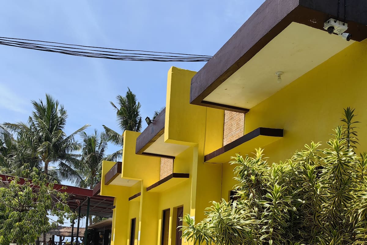 A yellow building with a covered outdoor seating area and a pathway leading to it.