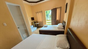 Habitació d'hotel amb dos llits, una taula petita, un sofà i una finestra amb cortines.