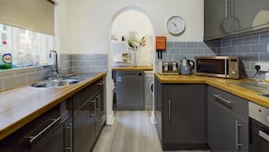 A modern kitchen with a dishwasher, microwave, toaster, and a clock on the wall. - Rondeva (Chester)