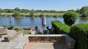 A patio area with a view of a lake, stone steps, and a white fence. - Rondeva (Chester)