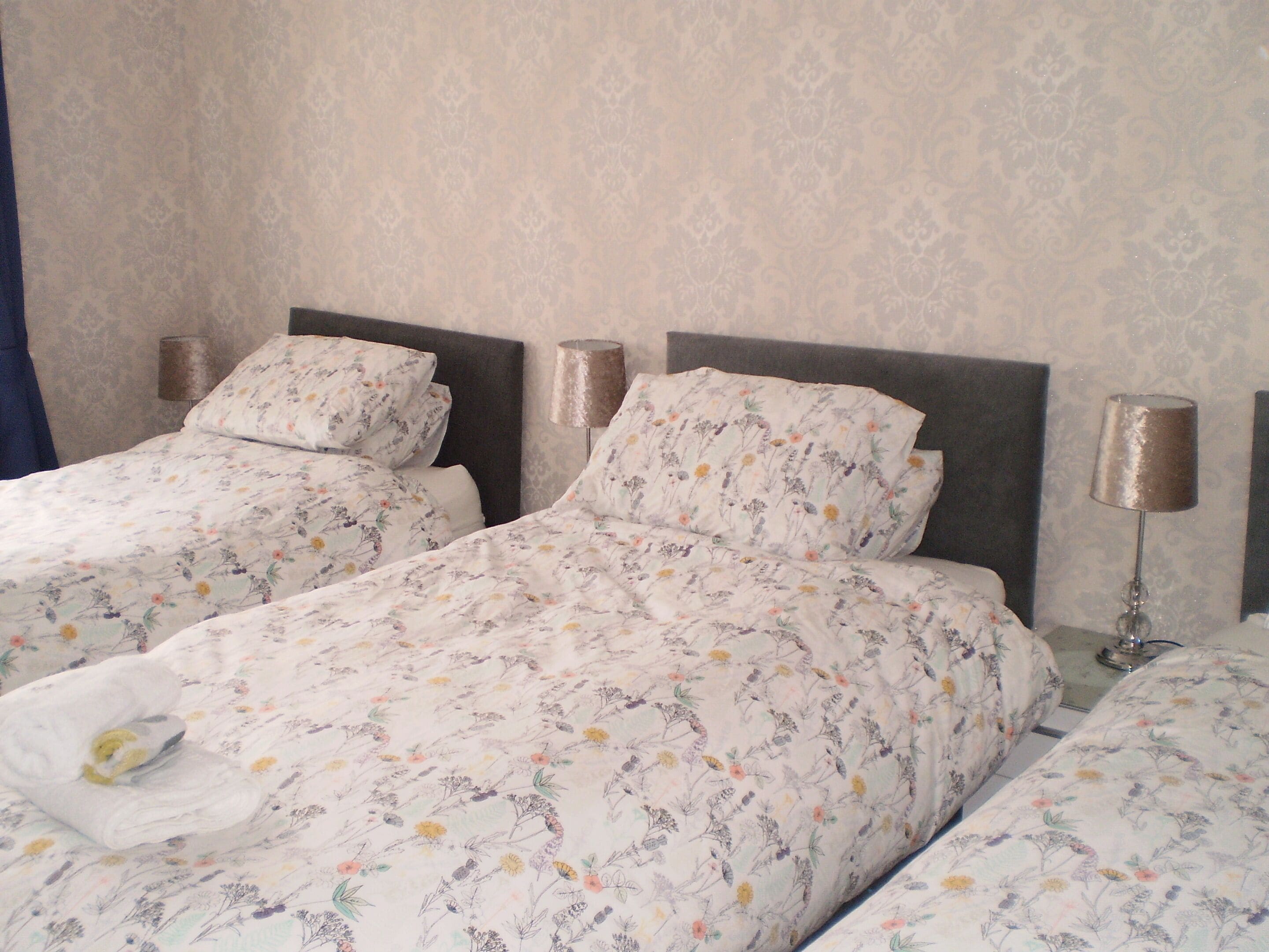A hotel room with two beds, floral bedding, and bedside lamps.