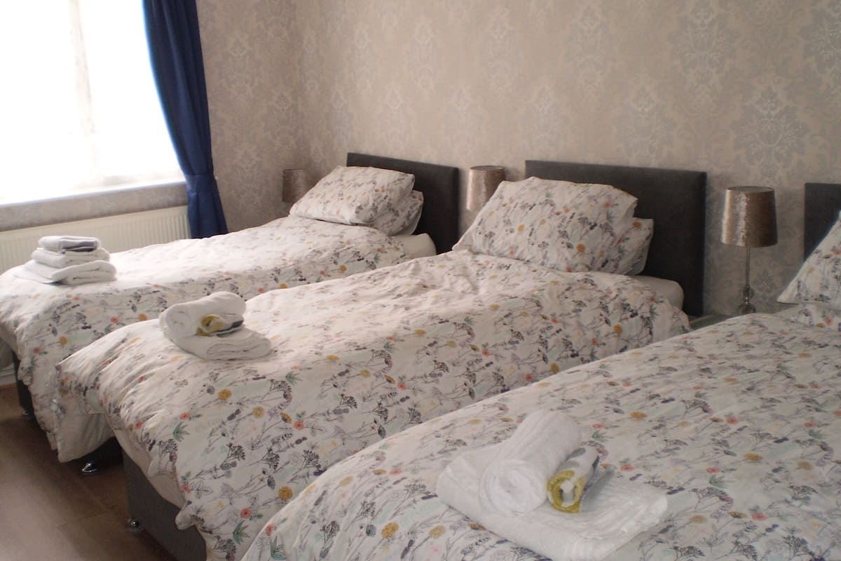 A hotel room with two beds, each with floral bedding and towels.