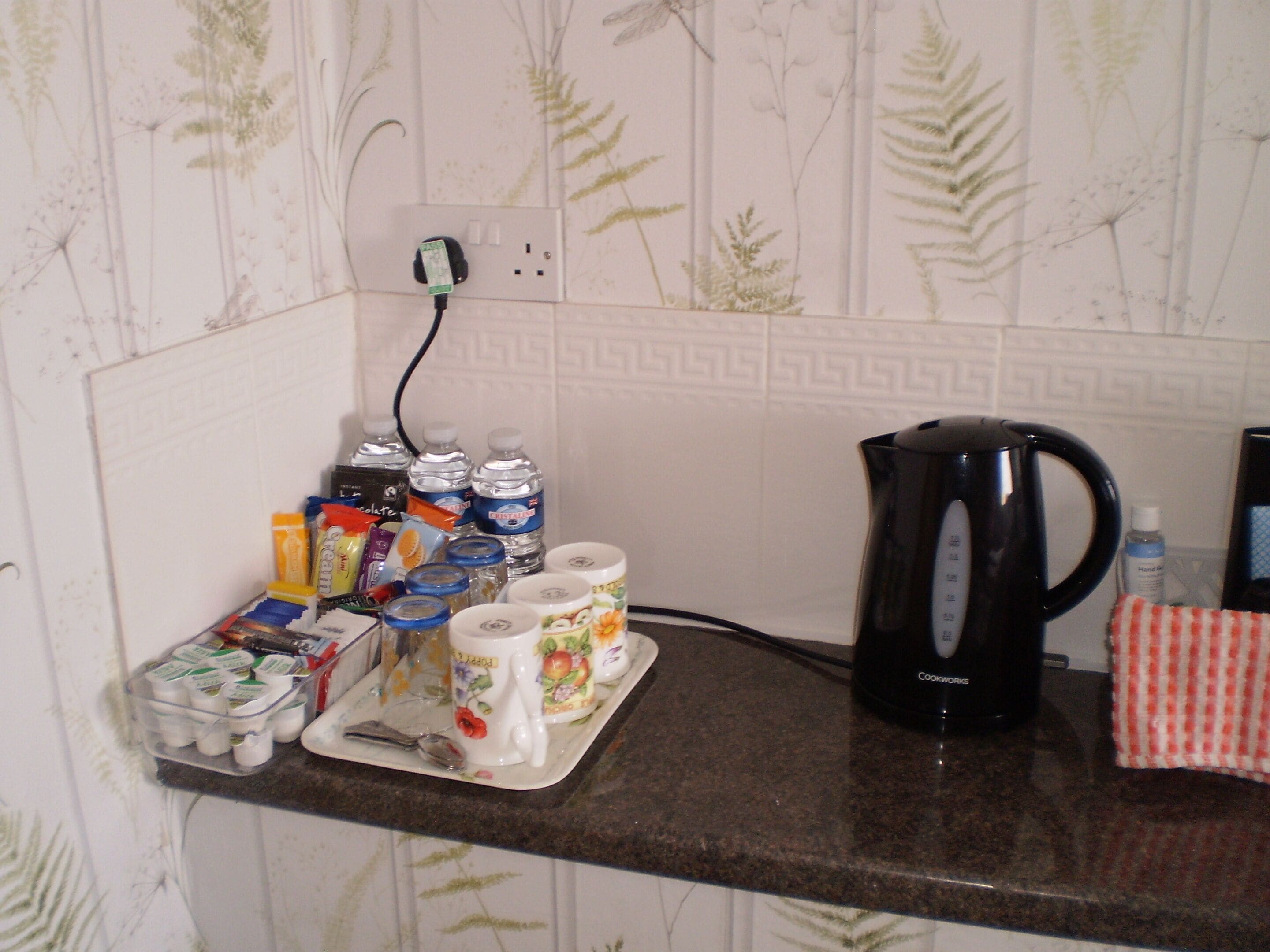 Een aanrecht met een koffiezetapparaat, waterflessen en diverse etenswaren.