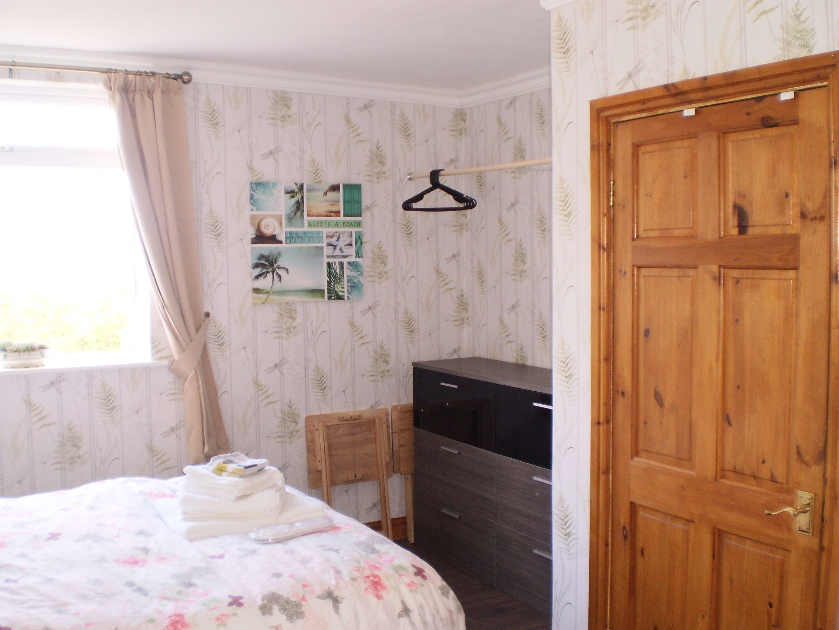 A bedroom with a bed, a dresser, a desk, and a wardrobe.