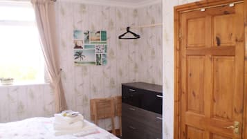 Un dormitorio con cama, cómoda, escritorio y armario.