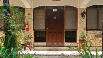 A building entrance with a wooden door, stone walls, and potted plants.