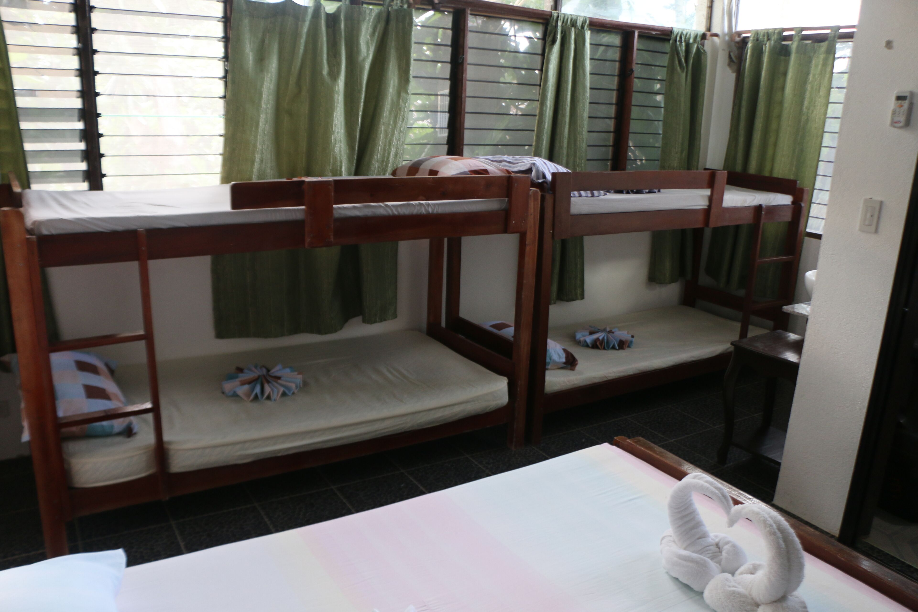 A room with bunk beds, a small table, and a window with curtains.
