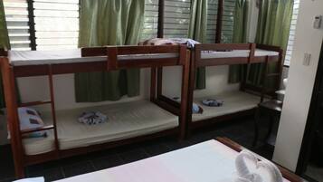 A room with bunk beds, a small table, and a window with curtains.