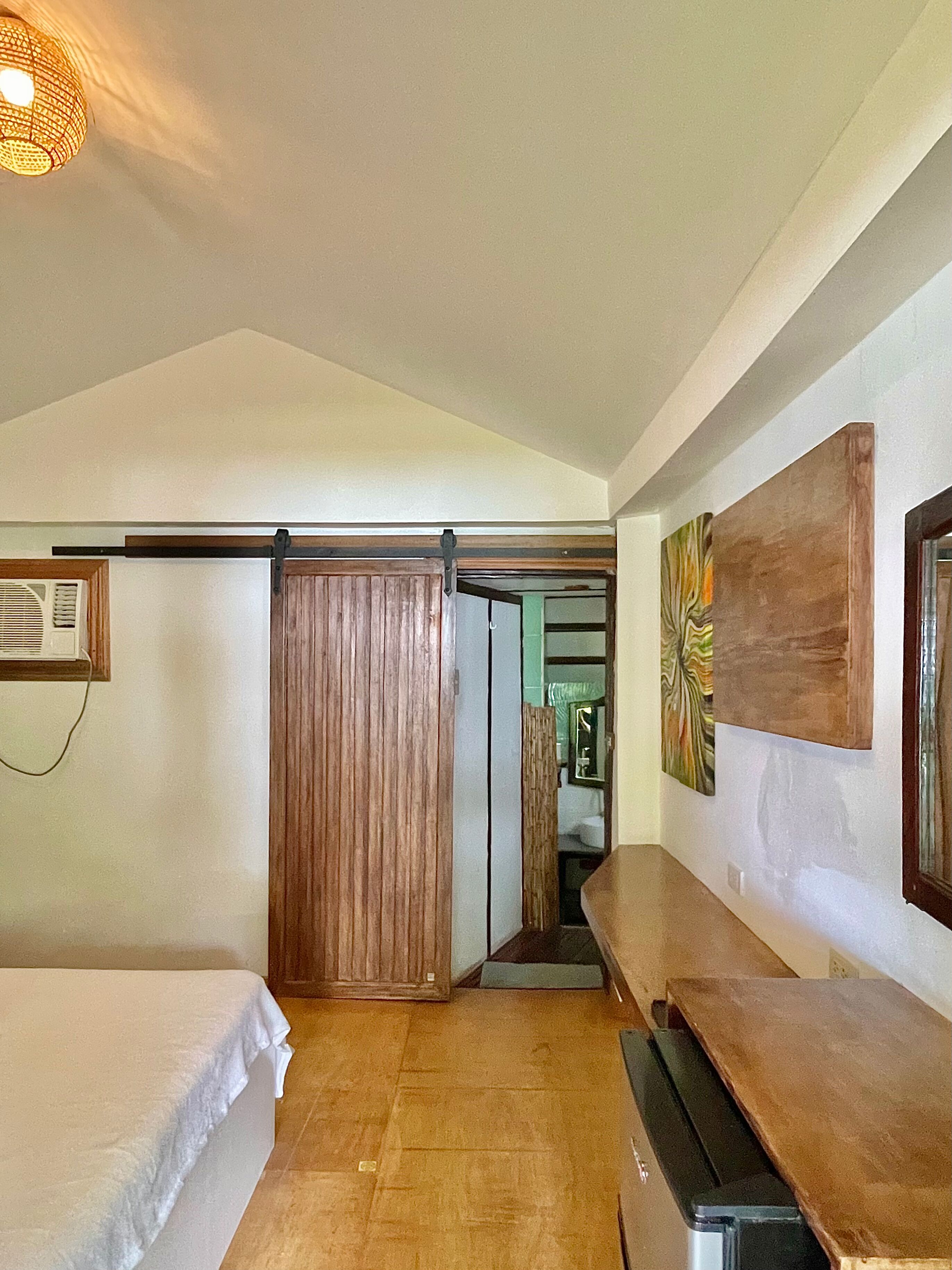 A bedroom with a bed, a bench, a sliding door, and a wall-mounted artwork.