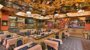 Un restaurante con varias mesas y cabinas, una zona de bar y un techo decorado con luces y adornos colgantes.