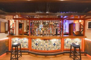 Zona de bar con mostrador de servicio, dos taburetes y un salpicadero de azulejos.