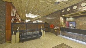 Una zona de recepción con un banco, mostrador y recepcionista, y un techo decorado con un estampado floral.