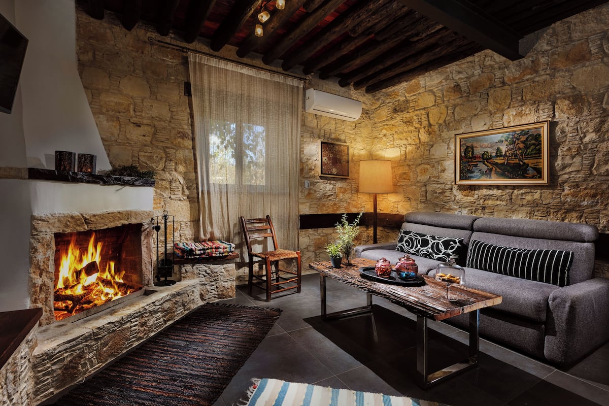 A cozy living room with a stone fireplace, a sofa, a coffee table, and a painting on the wall.