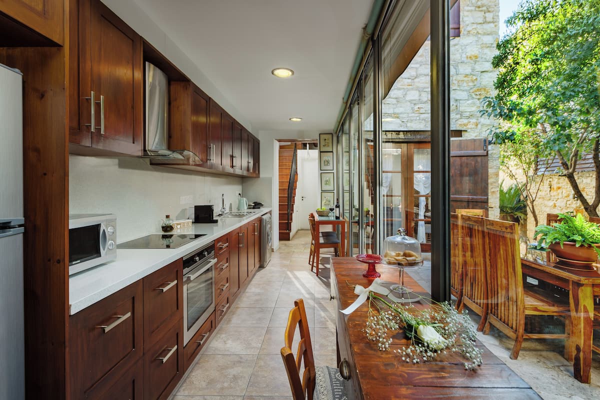 A modern kitchen with wooden cabinets, a microwave, and a dining area with a wooden table and chairs.