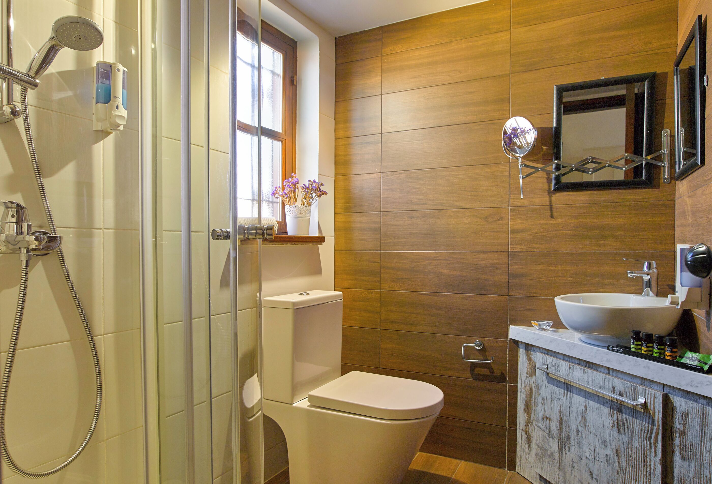 Een badkamer met een douche, toilet, wastafel en een raam.