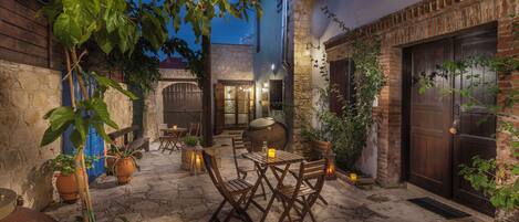 An outdoor patio with stone flooring, wooden furniture, and potted plants.