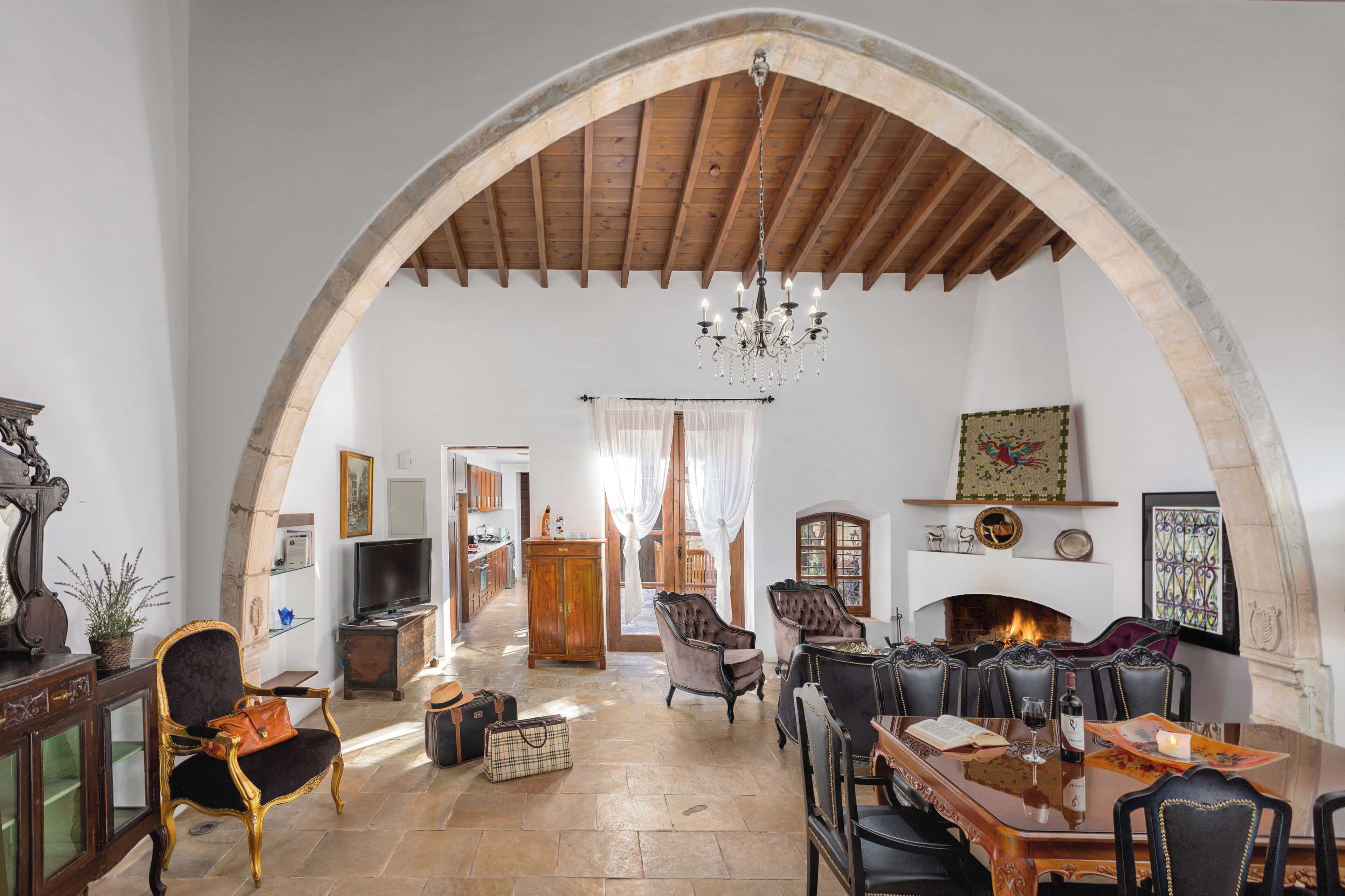 A spacious living room with an arched ceiling, a fireplace, and a dining area with multiple chairs.