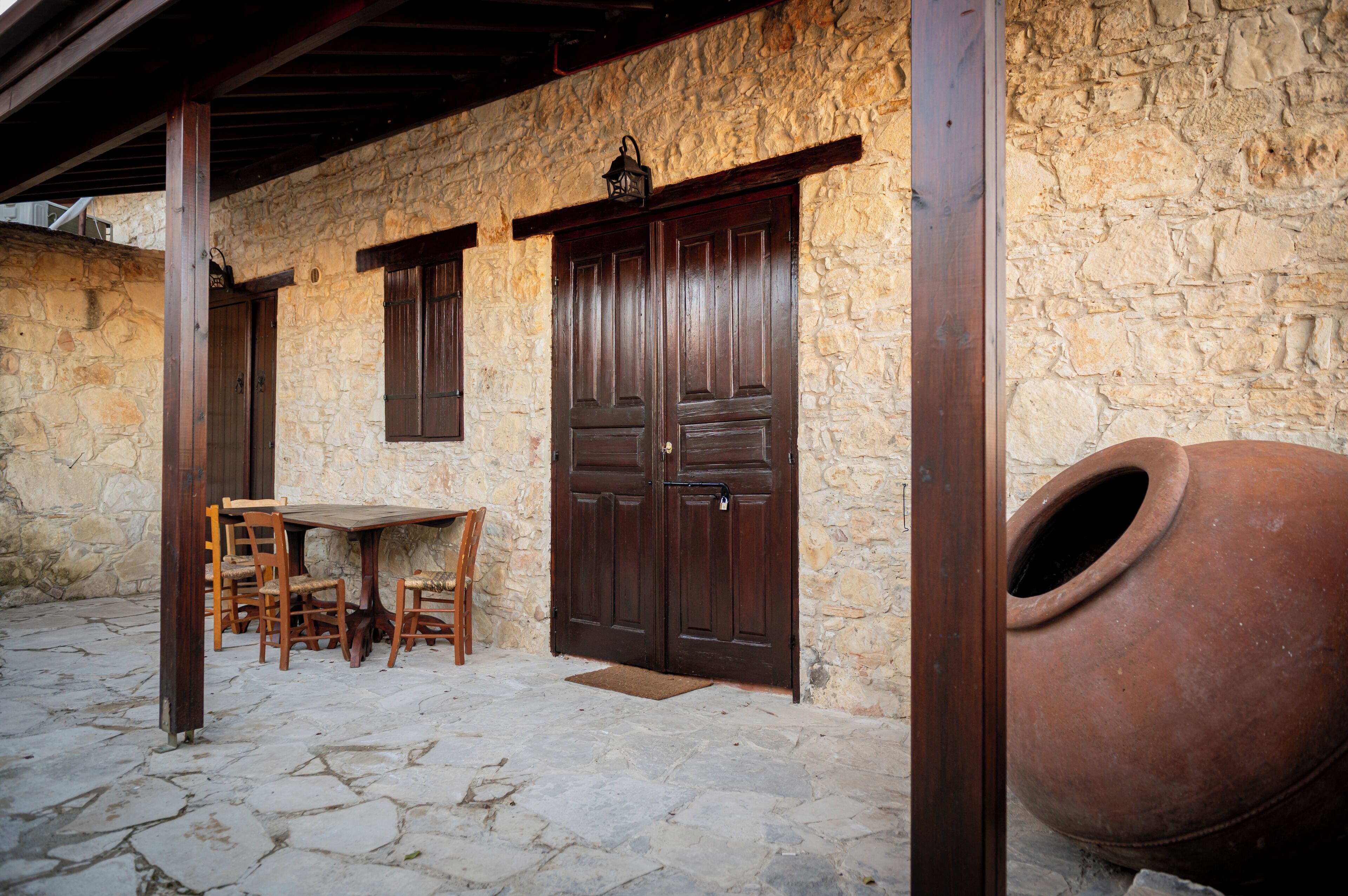A stone building with wooden doors and a large clay pot.