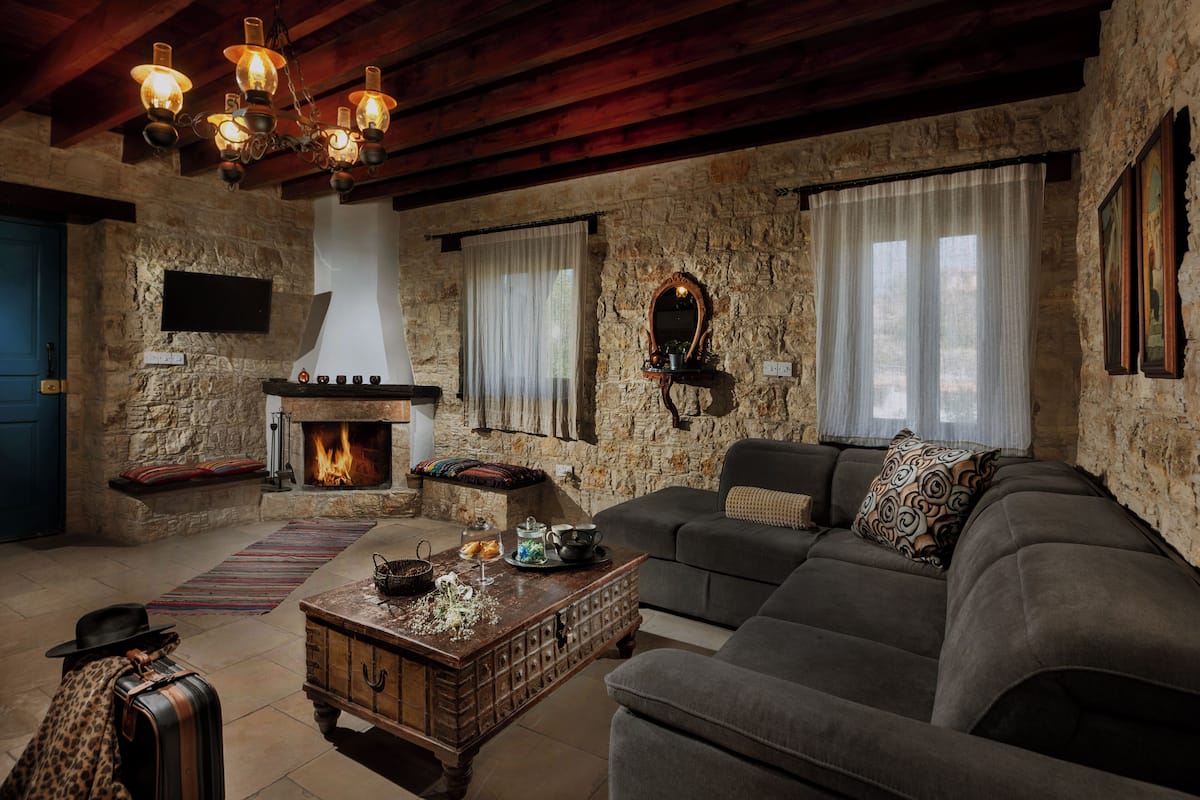 A rustic living room with a stone wall, a fireplace, a sofa, and a coffee table.