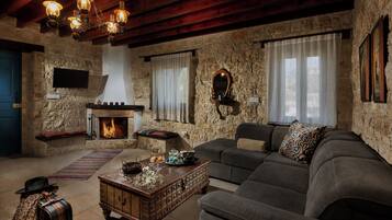 A rustic living room with a stone wall, a fireplace, a sofa, and a coffee table.