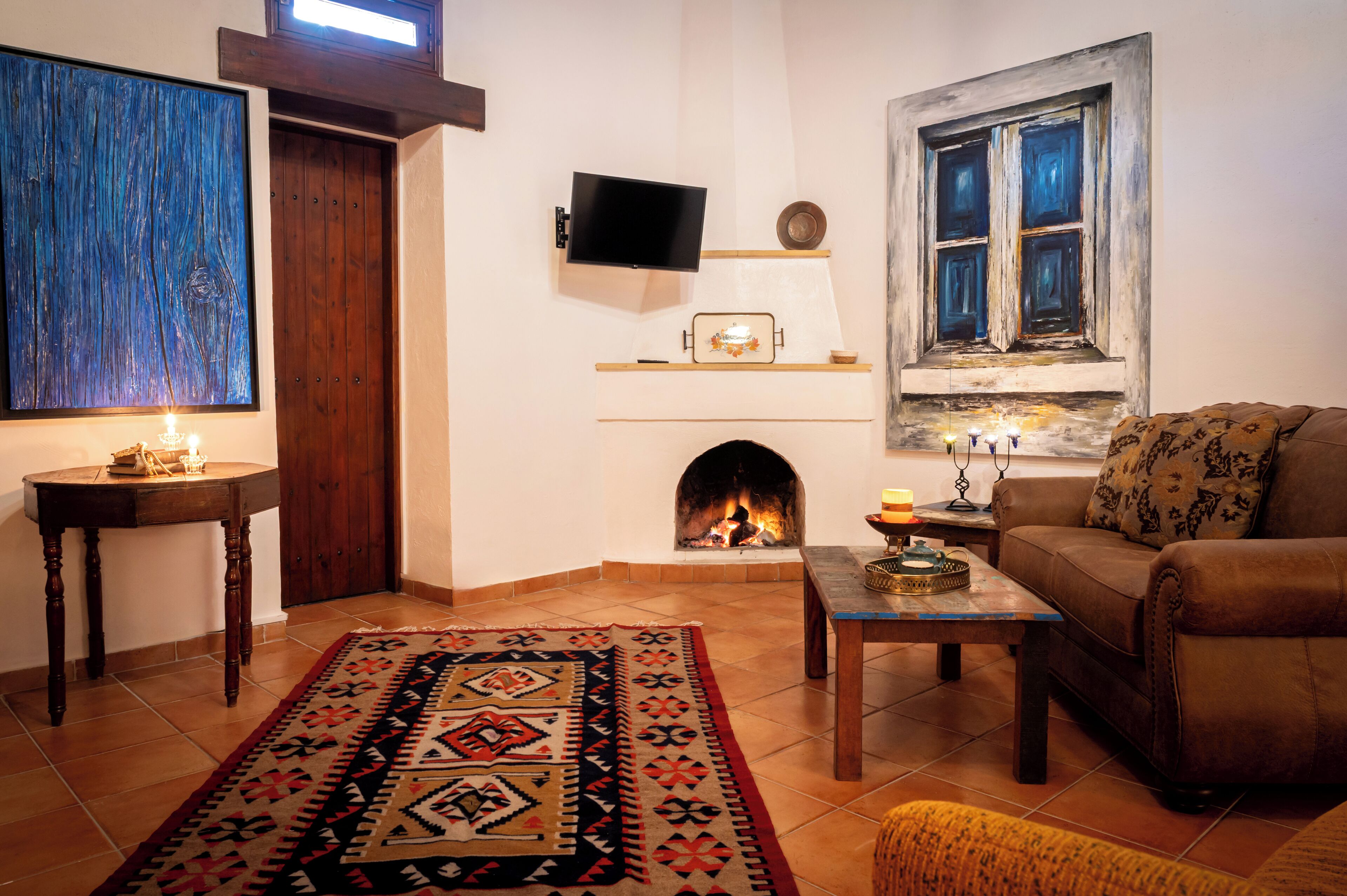 A cozy living room with a fireplace, a television mounted on the wall, and a patterned rug on the floor.