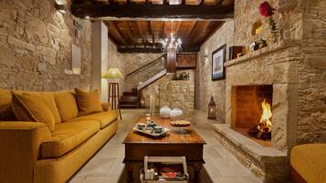 A cozy living room with a stone fireplace, a wooden staircase, and a sofa.