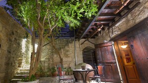 An outdoor patio with stone walls, a wooden door, and a table with chairs.